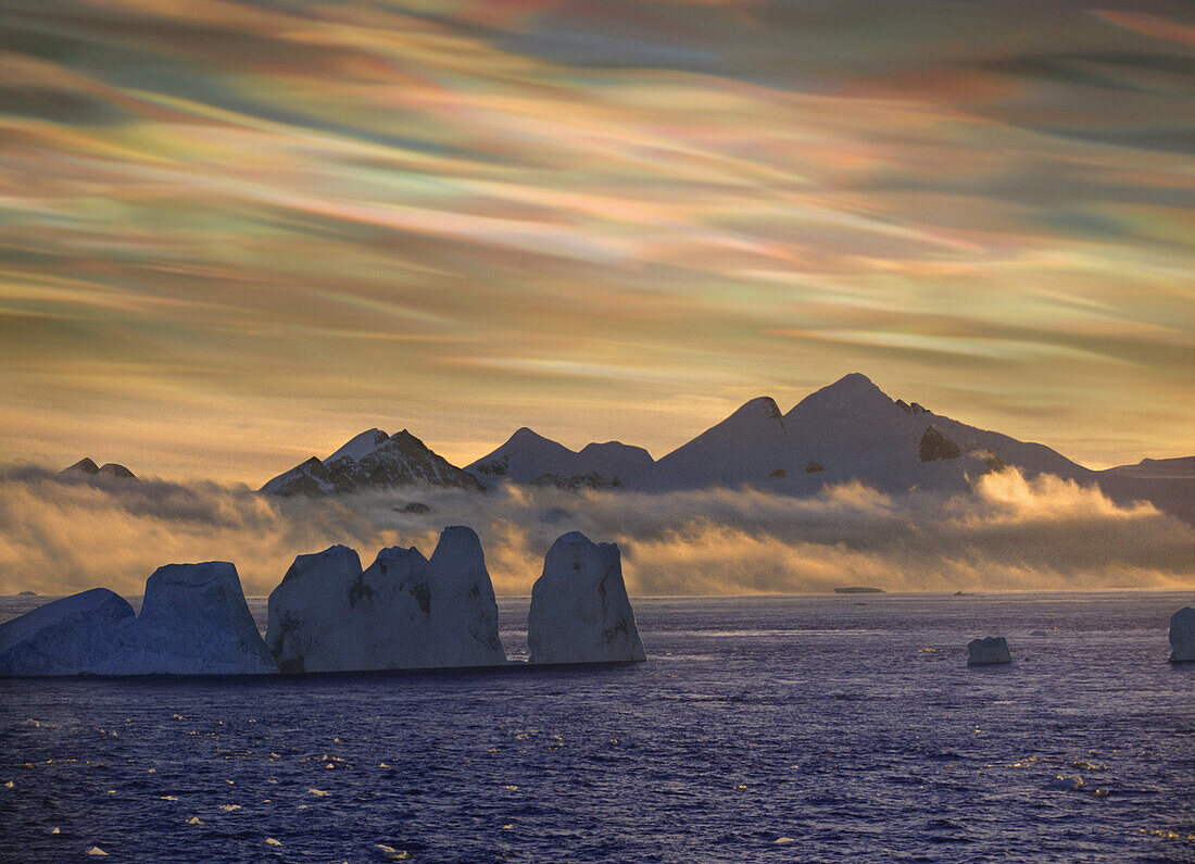 Perlmuttwolken über schneebedeckten Eisbergen, Antarktische Inseln, Antarktis