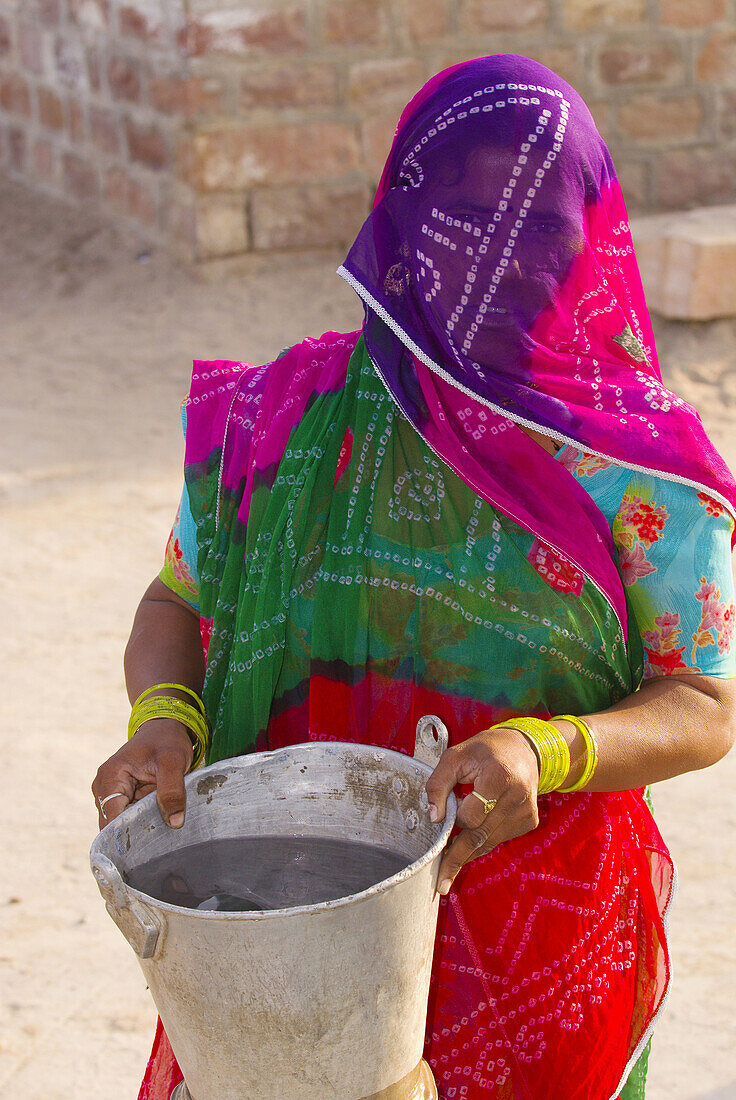 A veiled woman getting water from a well, Bishnoi tribal village, near Rohet, Rajasthan, India