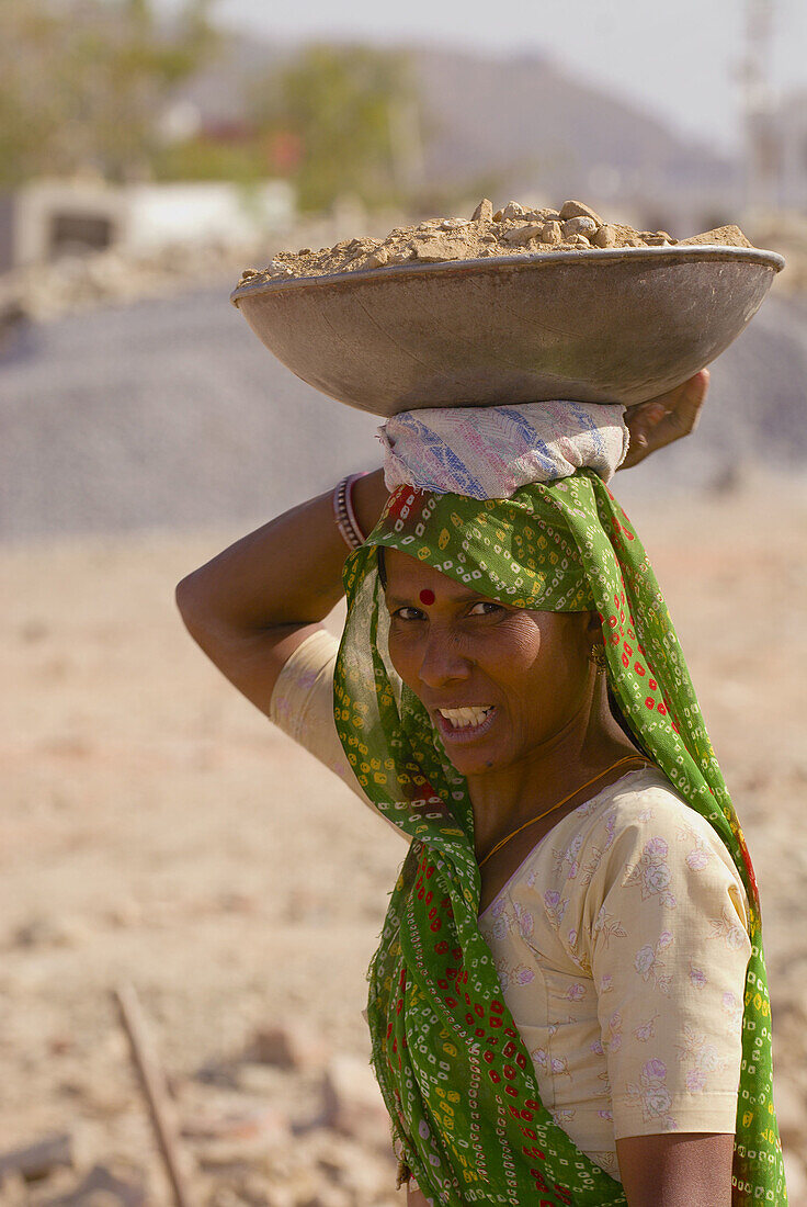 Women breaking up and carrying rocks at a construction site, Udaipur, Rajasthan, India