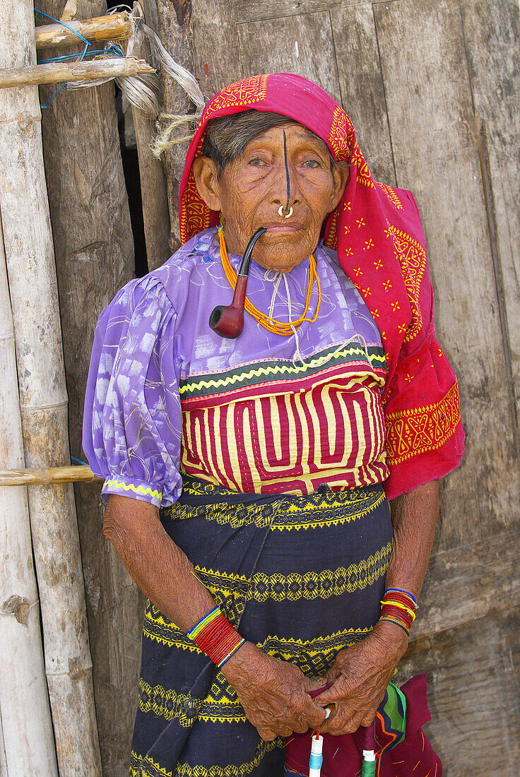 Kuna Indian woman with nosering smoking a pipe (wearing native costume with Mola embroderies), Corbisky Island, San Blas Islands (Kuna Yala), Caribbean Sea, Panama