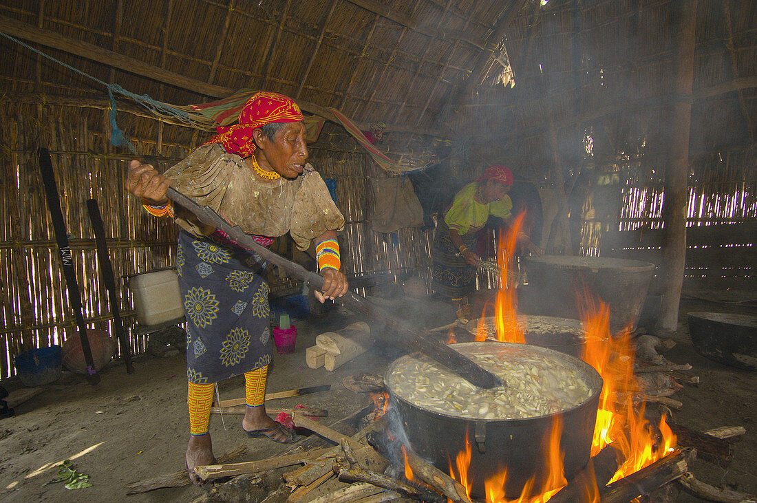 Kuna Indian women wearing native costumes with Mola embroderies cooking in a kitchen in a hut in their village on Corbisky Island, San Blas Islands (Kuna Yala), Caribbean Sea, Panama