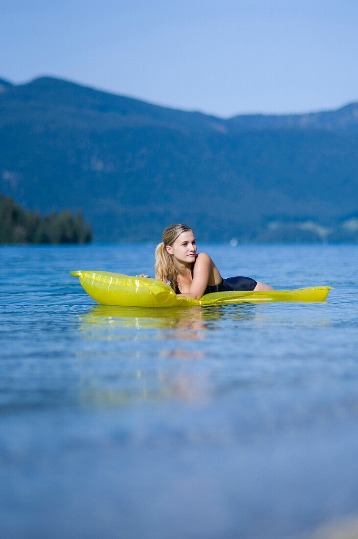 Junge Frau auf einer Luftmatratze auf dem Walchensee, Bayern, Deutschland