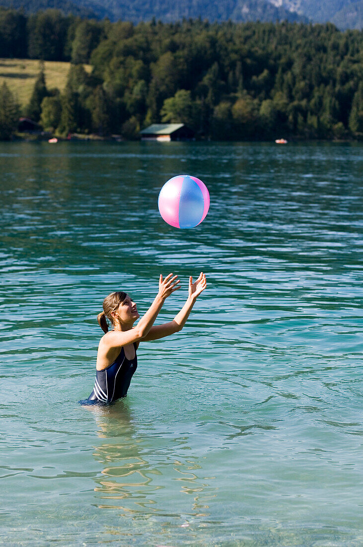 A young woman, girl, playing with a ball in Lake Walchensee, Upper Bavaria, Bavaria, Germany