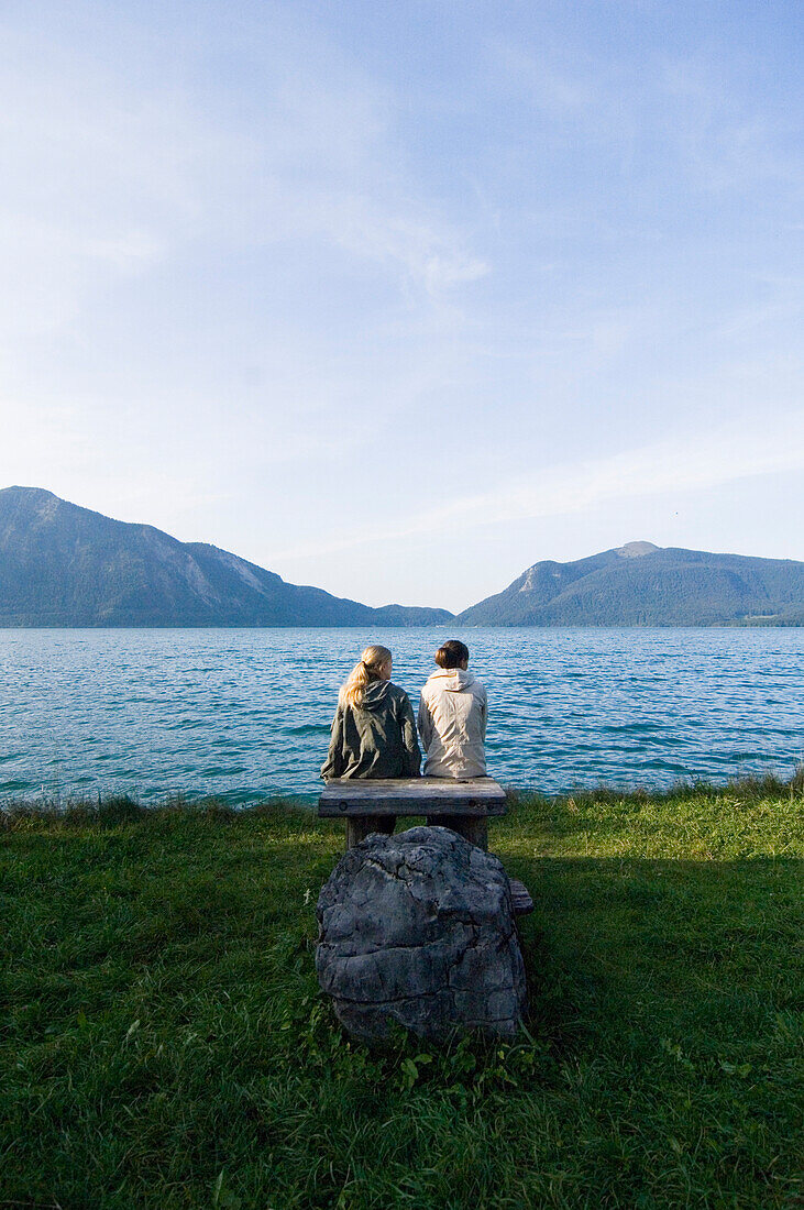 Two young women sitting on the lakeshore of Lake Walchensee, Upper Bavaria, Bavaria, Germany