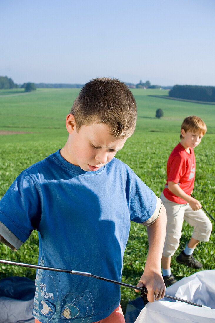 Two boys putting up a tent, Camping,  Bavaria, Germany