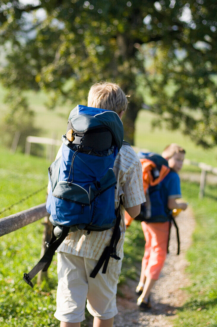 Zwei Kinder (6-8 Jahre) mit Rucksäcken wandern