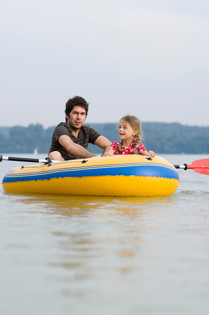 Vater und Tochter (3-4 Jahre) in einem Gummiboot auf dem Ammersee, Bayern, Deutschland