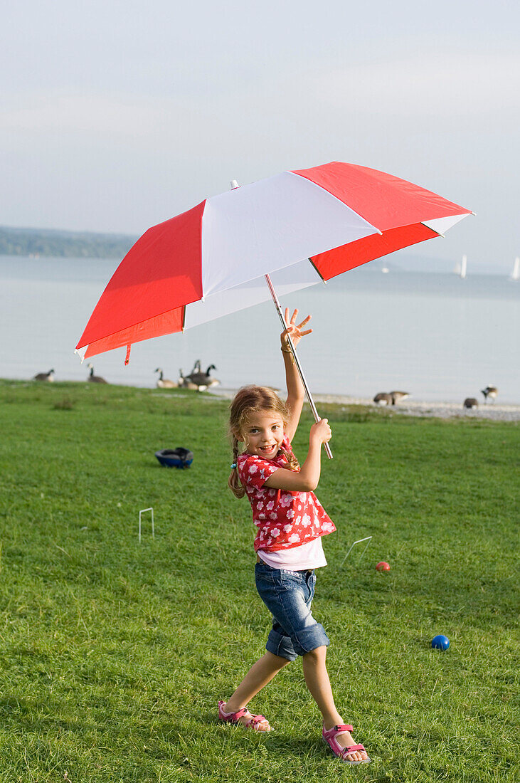 Mädchen (4-5 Jahre) trägt Schirm, Ammersee, Oberbayern, Bayern, Deutschland