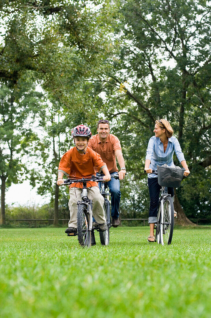 Familie fährt mit Fahrrädern über Wiese
