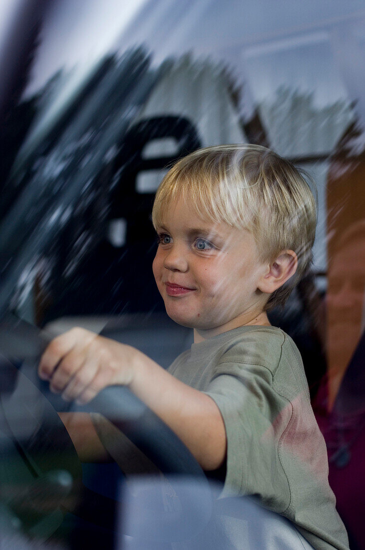 Boy sitting at the steering wheel of a camper van, Bavaria, Germany
