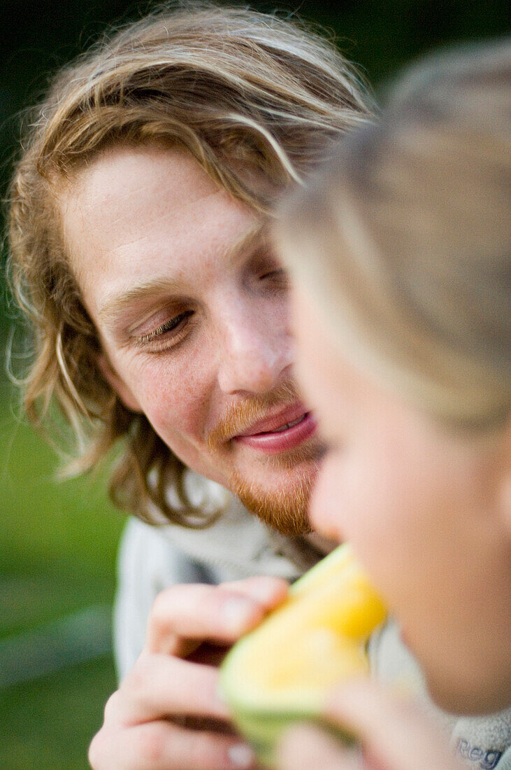 Young man feeding girlfriend with a slice of melon