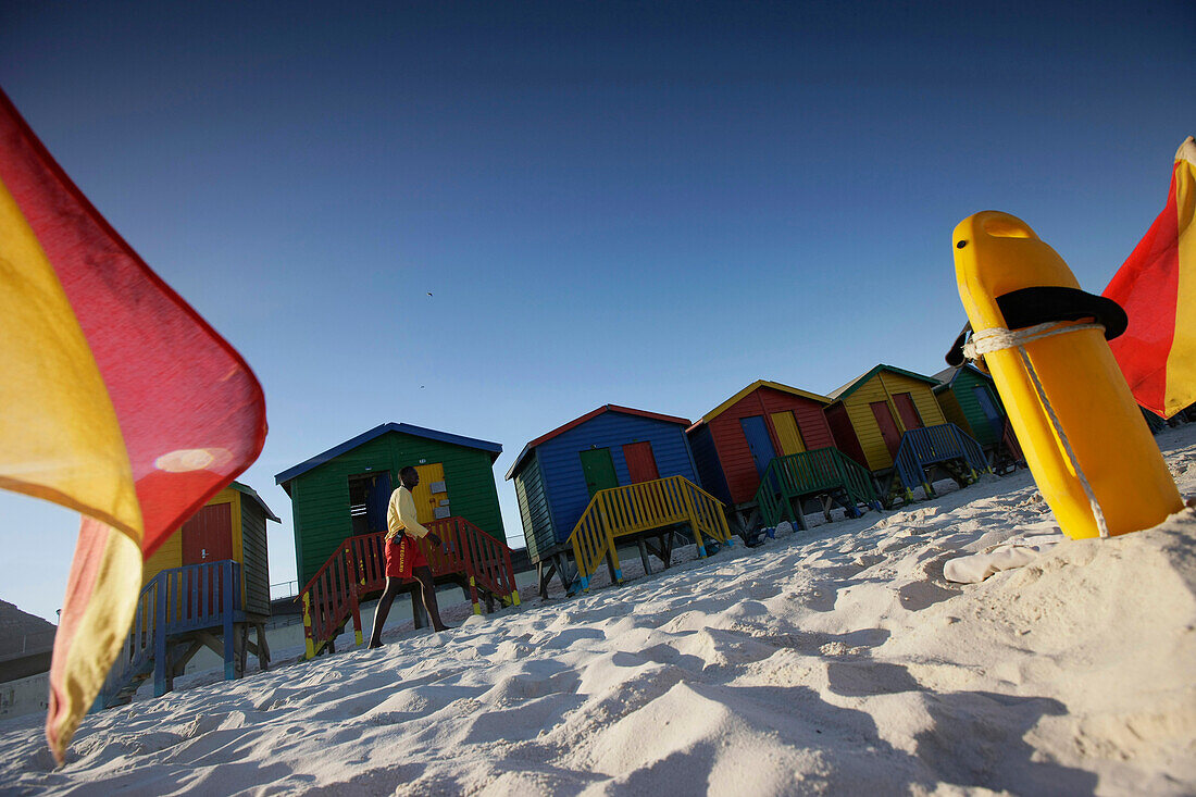 Beach huts and flags on the beach at Muizenberg, Cape Town, Western Cape, South Africa