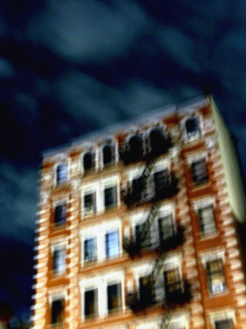 A New York apartment building is captured at night with a blury, pastel effect.