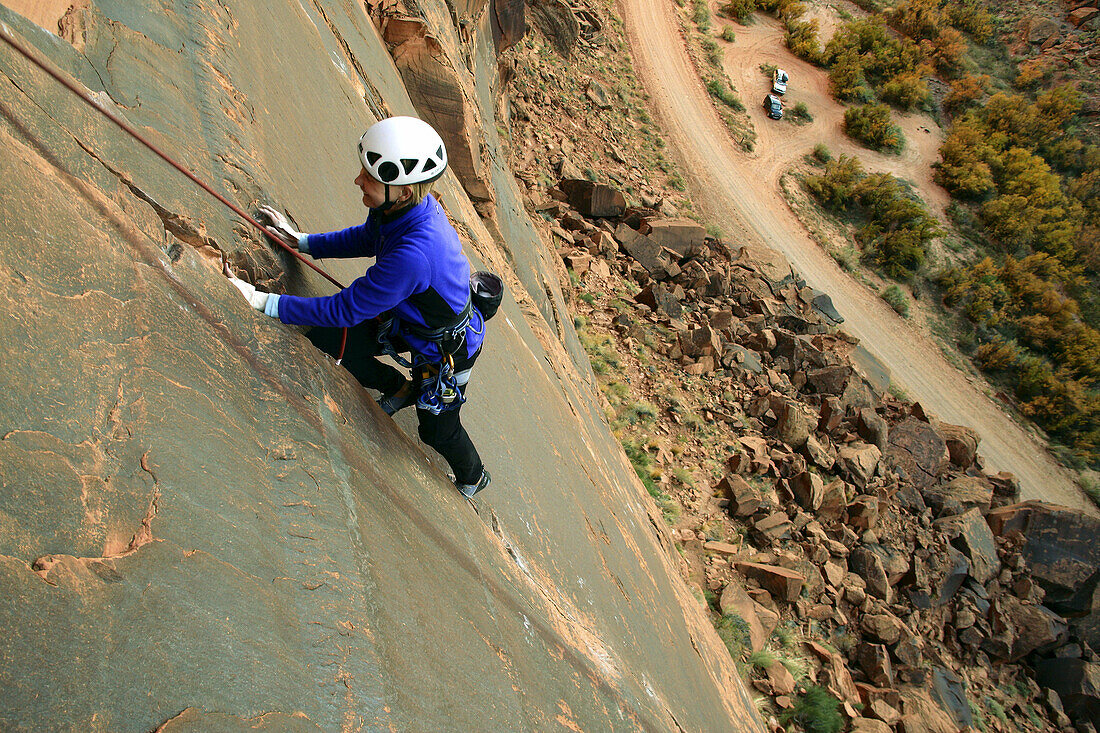 Female climber on route at the Ice Cream Parlor crag near Moab, Utah, USA
