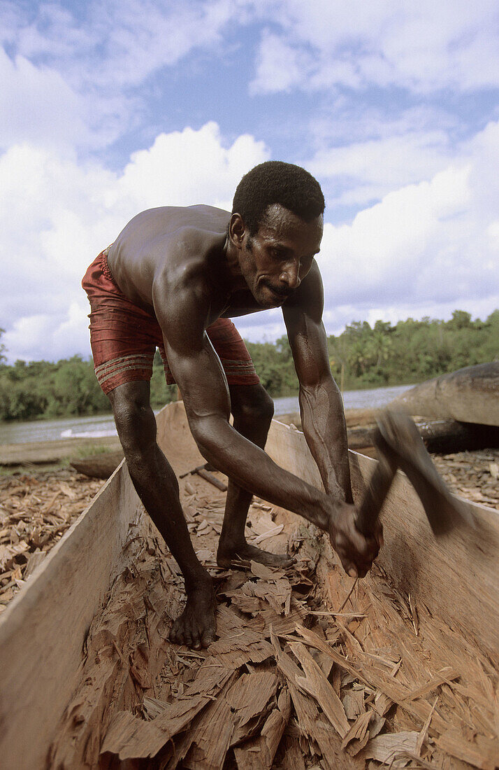 Asmat man building his canoe out of a timber, Western Papuasia, Former Irian-Jaya, Indonesia