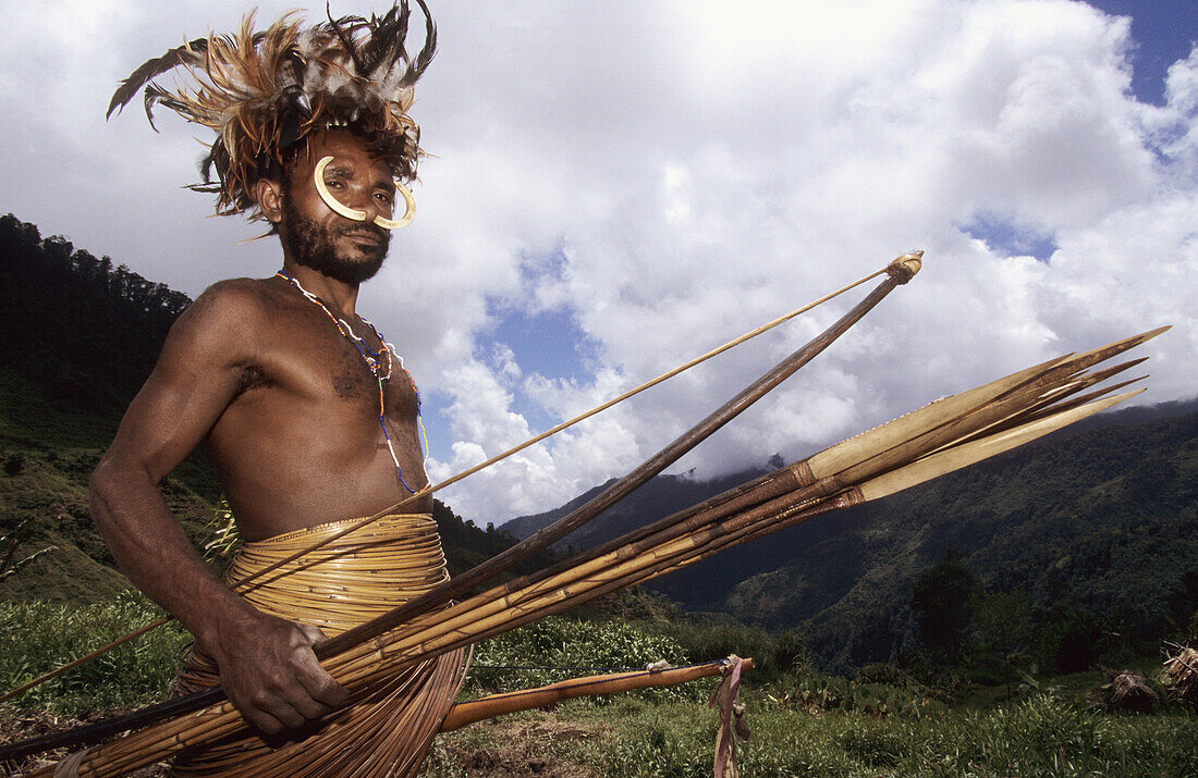 Yalis hunter with nose adornment made of wild pigs bones, rooster feathers head-dress, long penis case, bow and arrows, Western Papuasia, Former Irian-Jaya, Indonesia