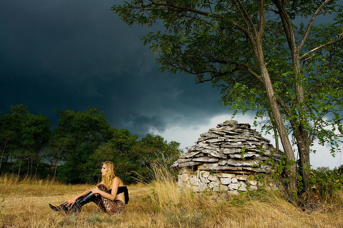 Young woman in front of Istrian kazun stone hut just before the storm, Croatia, Europe