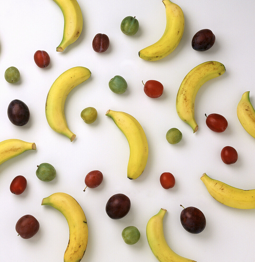 Bananas and plums on white background
