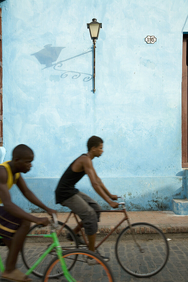 Façade in Plaza de San Juan de Dios. Young people cycling. Camagüey. Cuba.
