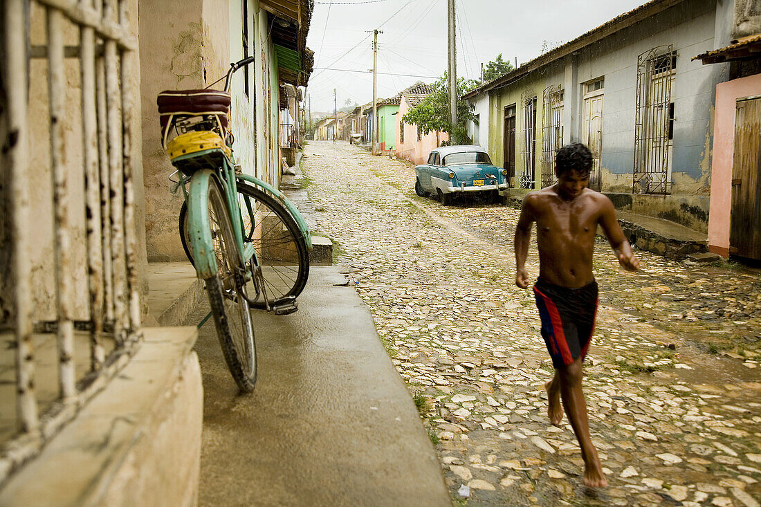 Young man running to protect himself from the rain. Trinidad. Sancti Spíritus province, Cuba