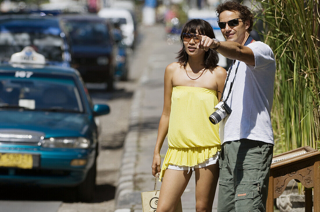 couple standing on sidewalk and pointing