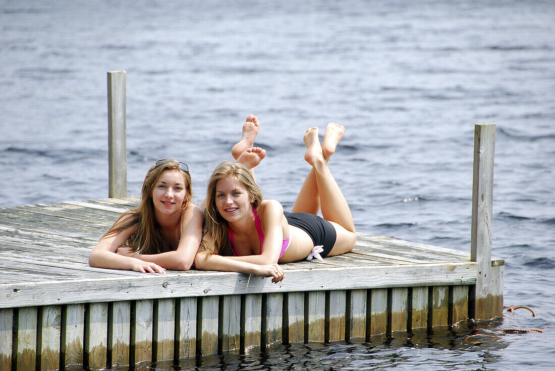 sisters 13 and 18 yrs laying on dock together