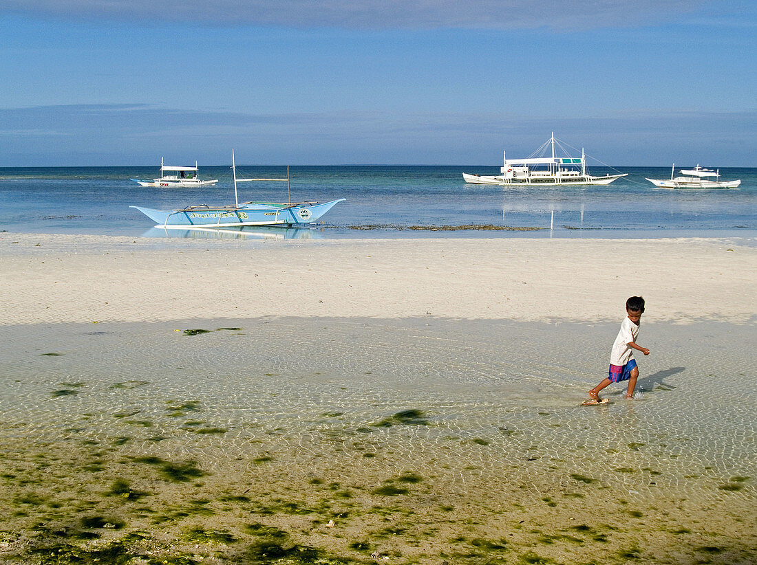 boy playing at low tide, Malapascua Island, Philippines