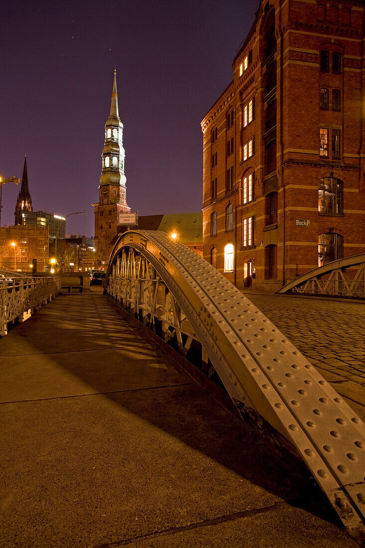 View over bridge to St. Catherine's Church and St. Nikolai's Church at night, Speicherstadt, Hamburg, Germany