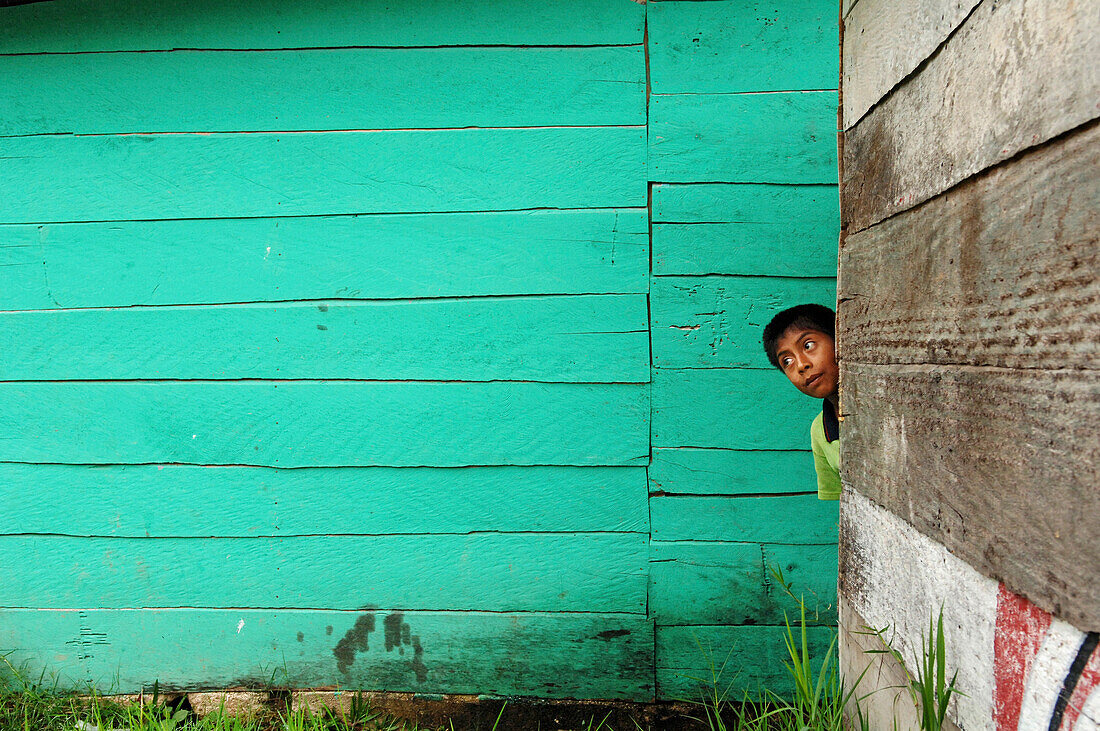 Junge versteckt sich hinter eine Hüttenwand bei den Wasserfällen von Aqua Azul, tropisches Tiefland von Chiapas, Mexiko