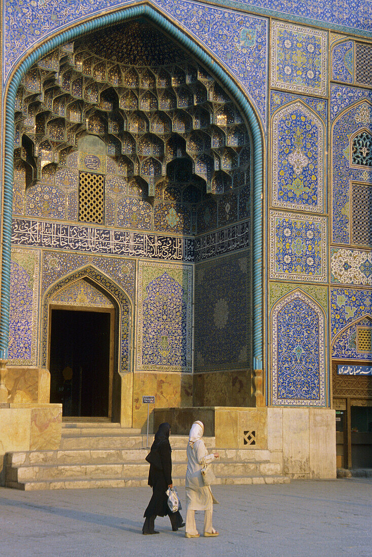 Women passing by Sheykh Lotfollah Mosque in Emam Khomeini Square. Esfahan, Iran