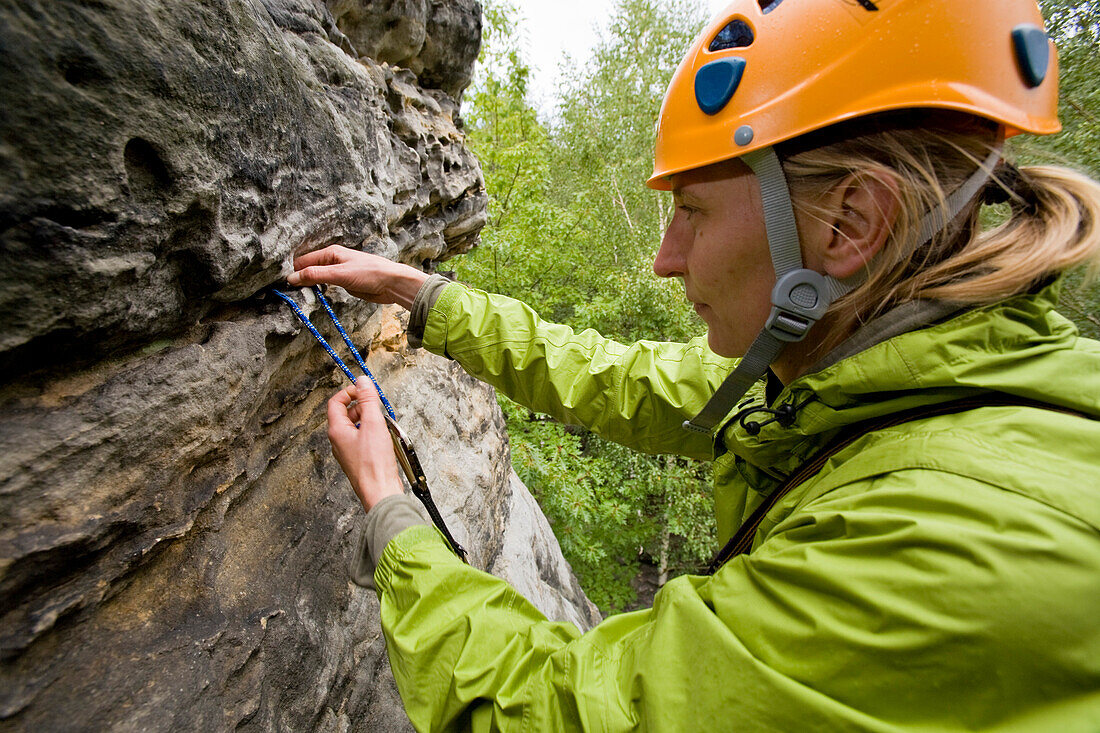 Eine junge Frau, eine Kletterin knüpft eine Sanduhrschlinge in der Route Alter Weg, am Wegelagerer Felsen, Bielatal, Elbsandstein, Sächsische Schweiz, Sachsen, Deutschland, MR
