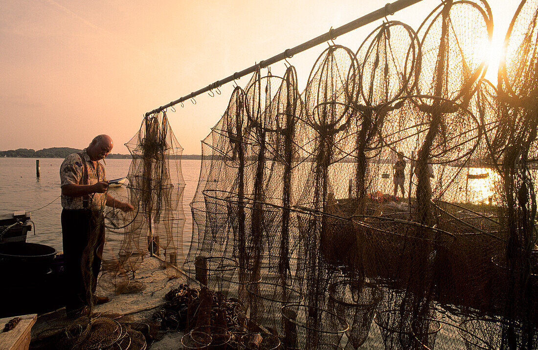 Fischer flickt seine Netze im Hafen am Abend, Schleswig, Schleswig-Holstein, Deutschland, Europa