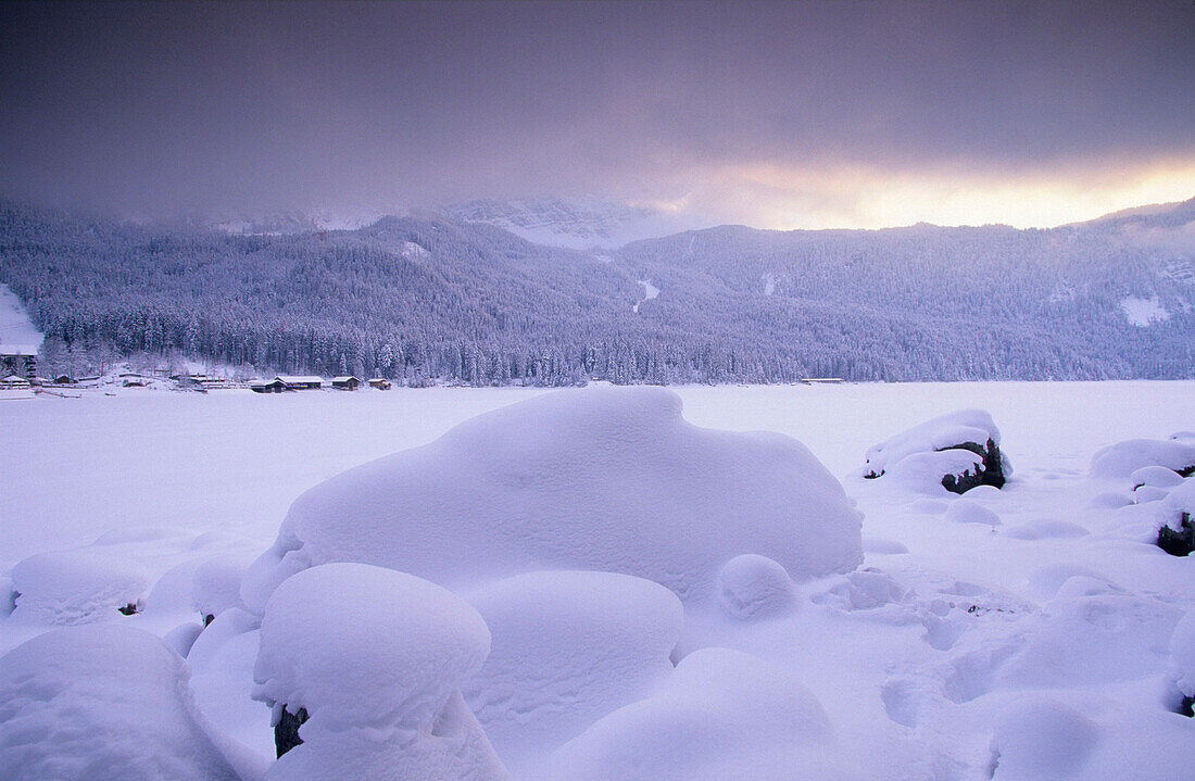 Europa, Deutschland, Bayern, bei Grainau, schneebedeckte Steine auf dem zugefrorenen Eibsee mit den bayrischen Alpen