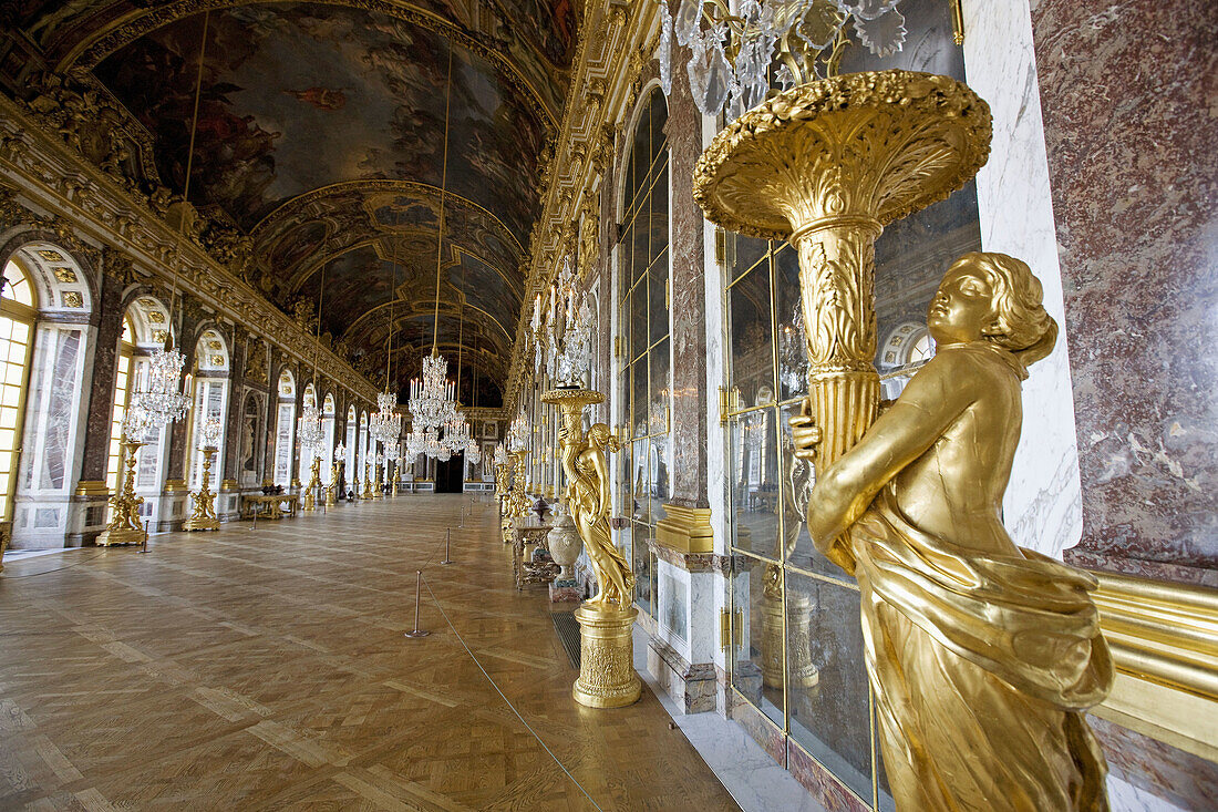 Golden statues holding lamps in the Hall of Mirrors, Palace of Versailles. France