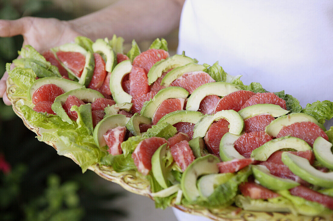 Close-up of avocado and red grapefruit salad on tray.