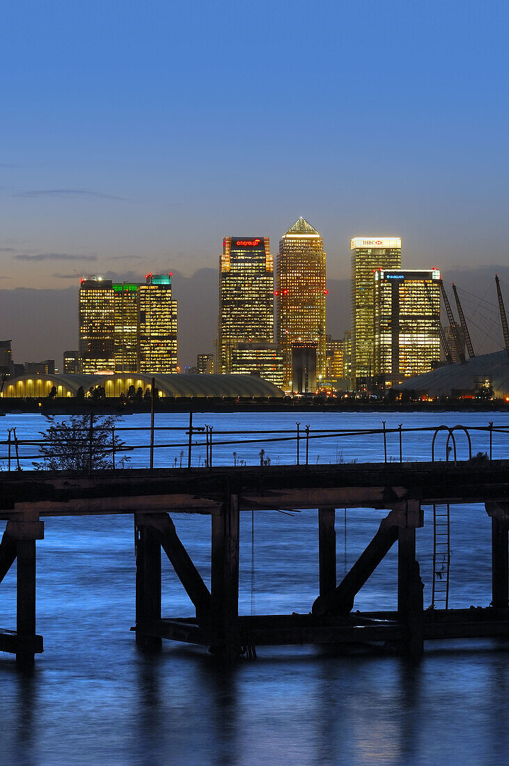 Canary Wharf and skyscraper at night across river Thames with pier, London. England, UK