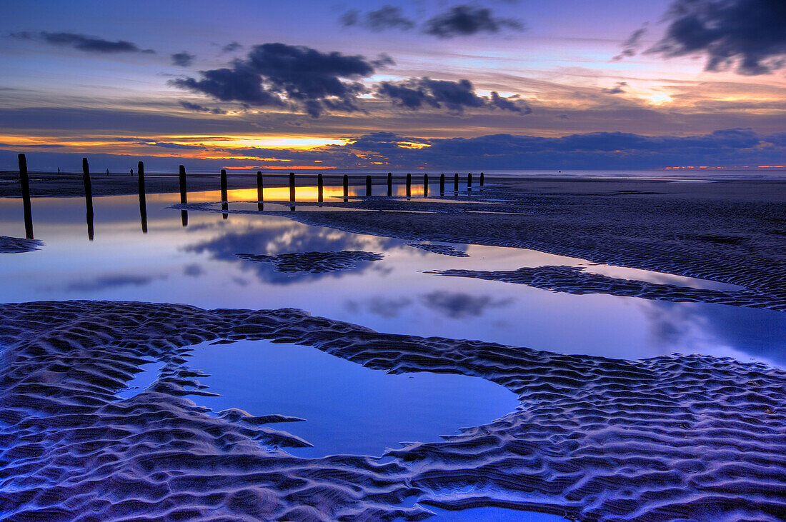 beach and wooden groyne at sunset with large pools of water and cloud reflections blackpool lancashire england uk europe