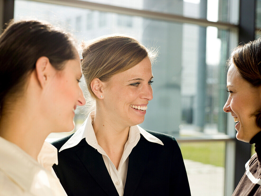 Three businesswomen talking and laughing, Munich, Bavaria, Germany
