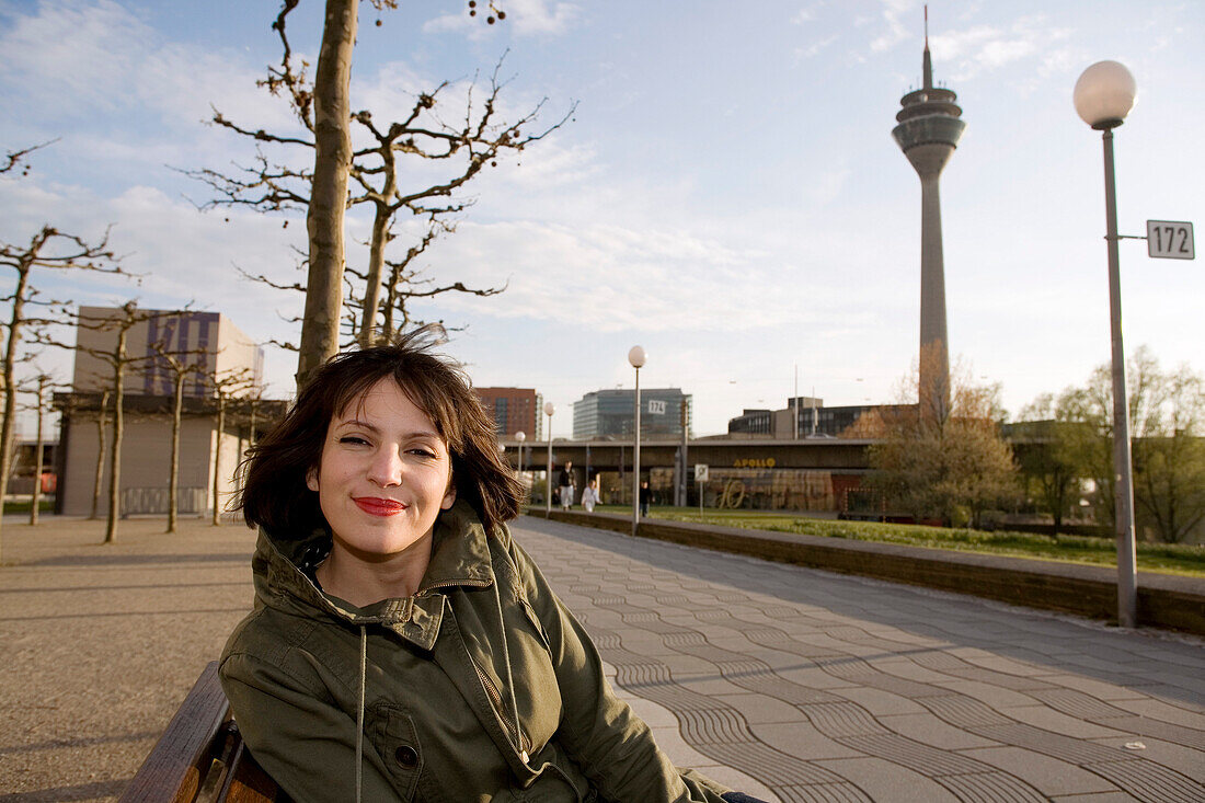 Young woman sitting on a bench at the promenade, Duesseldorf, North Rhine-Westphalia, Germany