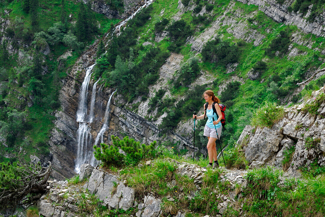 young woman hiking in front of waterfall, Soiern range, Karwendel range, Upper Bavaria, Bavaria, Germany