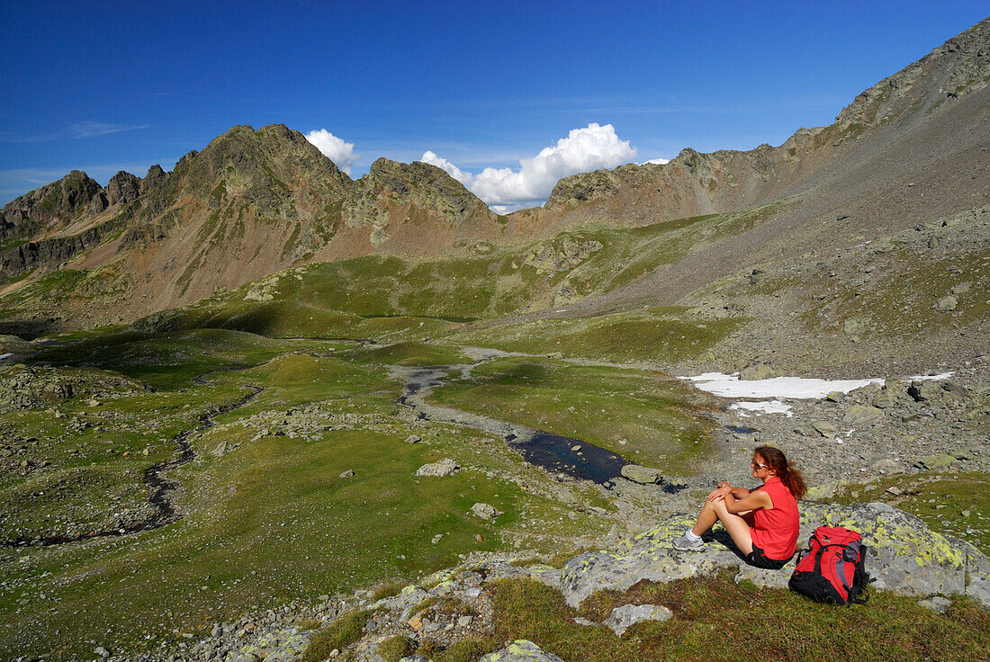 young woman resting on the way to notch Hörtlanger Scharte beneath Tagewaldhorn, Sulzspitze in background, Sarntal range, South Tyrol, Alta Badia, Italy