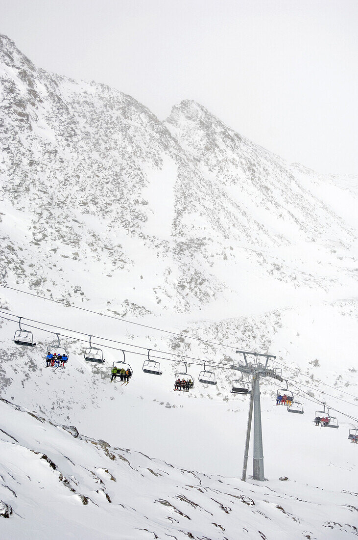 Skiers in chair lift, Schnalstal valley, South Tyrol, Italy