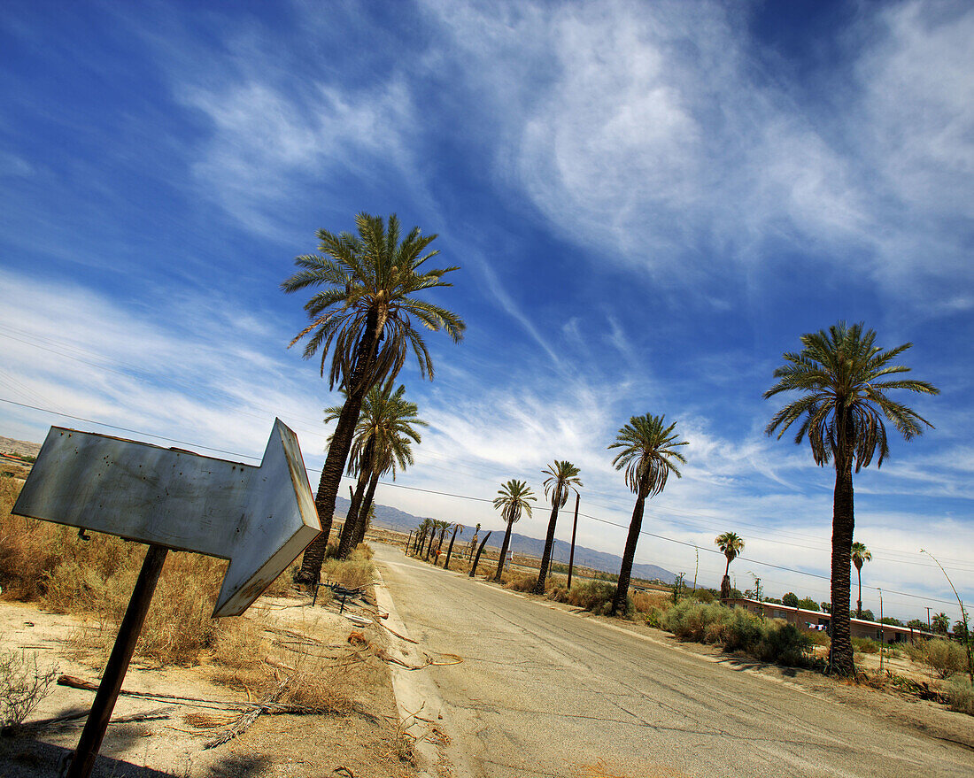 Old arrow sign on old desert roadway