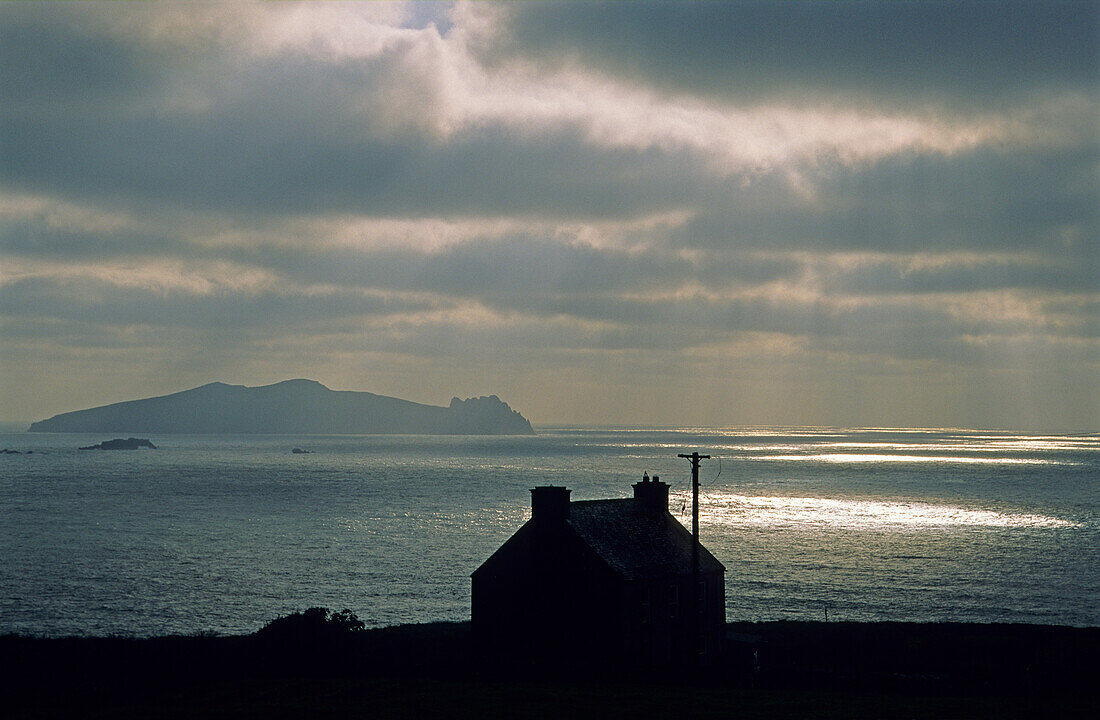 Sonnenstrahlen scheinen durch eine dunkle Wolkendecke über Blasket Island, County Kerry, Irland, Europa