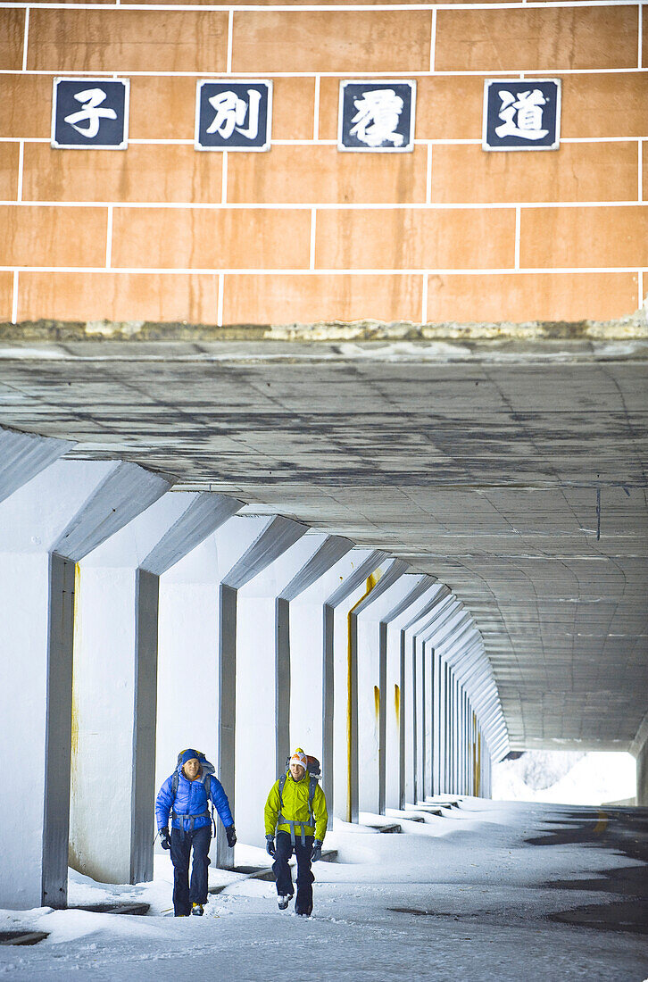 Two men walking through a pedestrian underpass in winter, Hokkaido, Japan, Asia