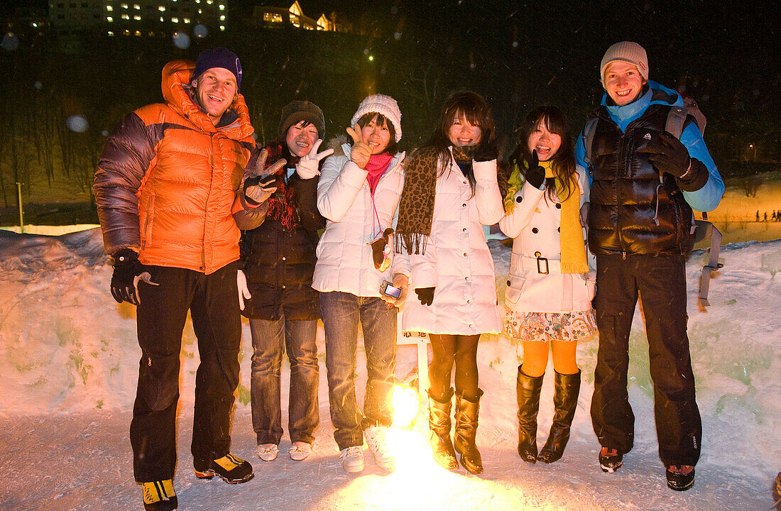 Zwei Europäer und japanische Frauen stehen abends im Schnee, Hokkaido, Japan, Asien