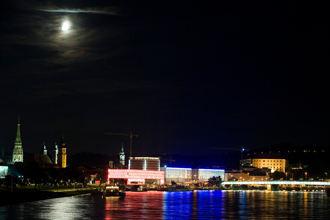 Vollmond scheint über dem beleuchteten Museum für moderne Kunst an der Donau, Linz, Oberösterreich, Österreich