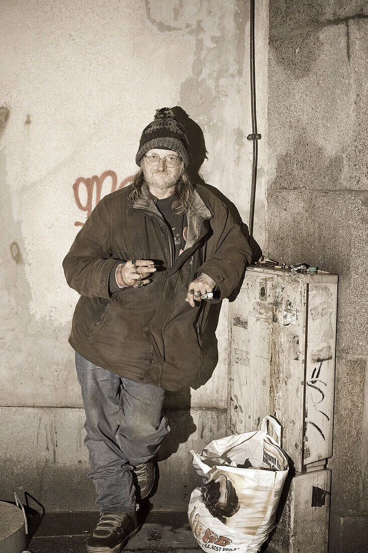 A homeless person with a plastic bag standing in front of a wall, Linz, Upper Austria, Austria