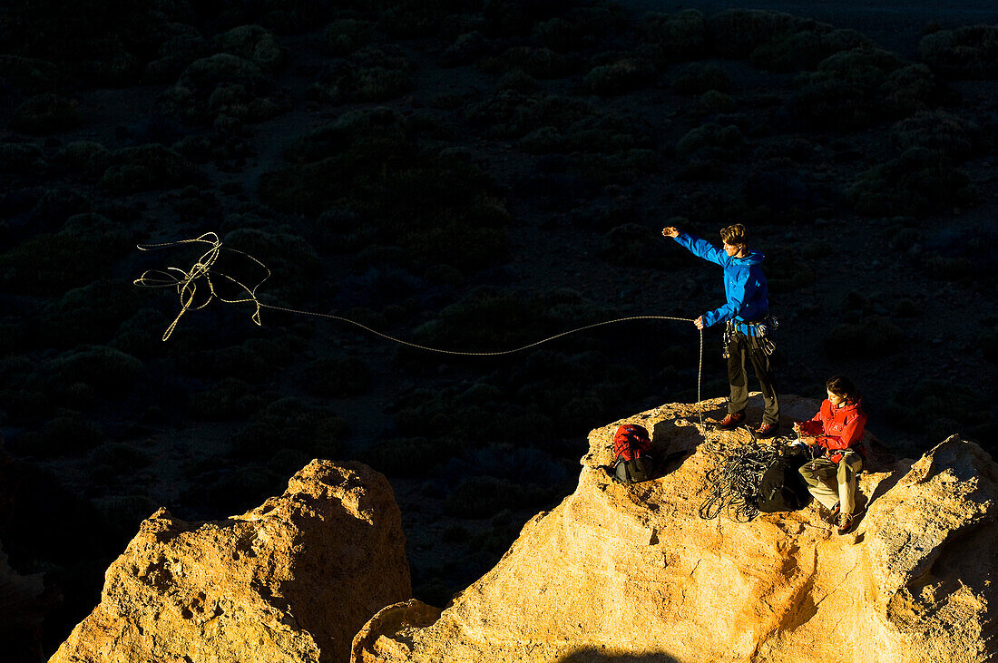 Ein Paar auf einem Berggipfel, der Mann wirft ein Seil, Teide Nationalpark, Teneriffa, Kanarische Inseln
