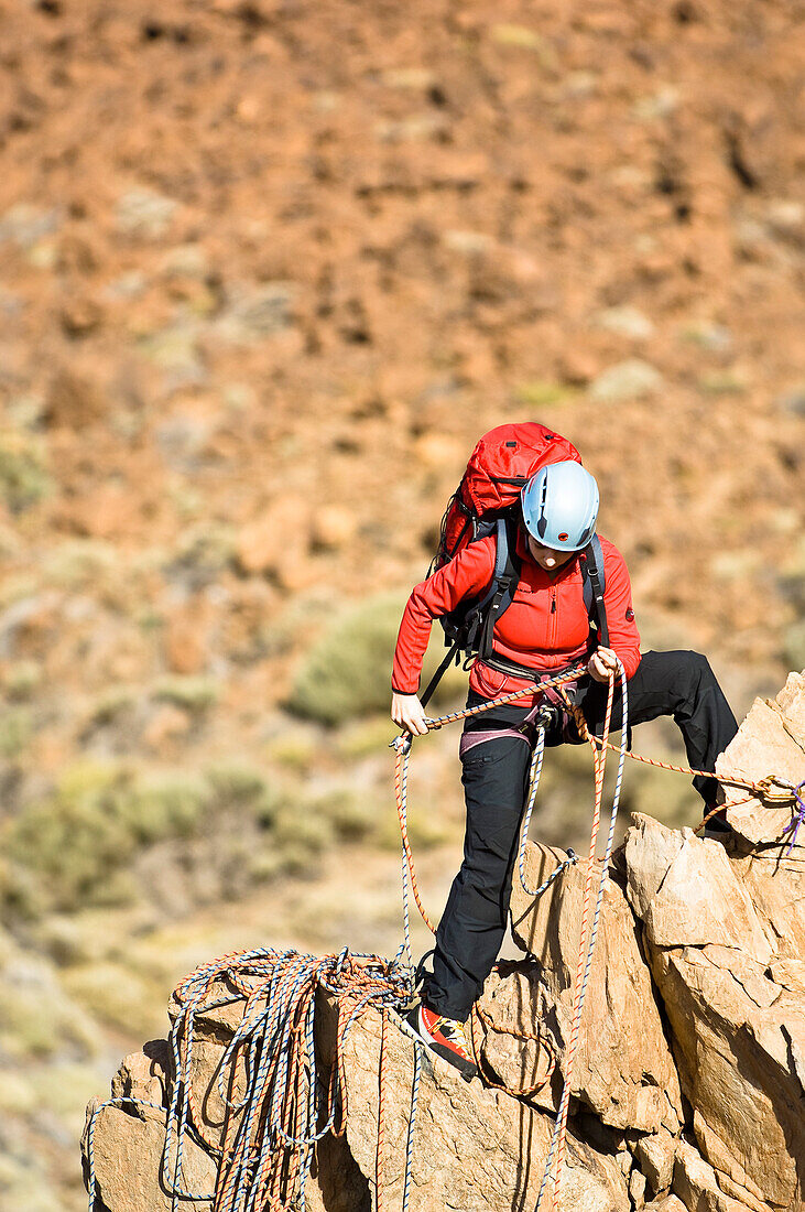 Frau klettert auf einem Grat im Teide Nationalpark, Teneriffa, Kanarische Inseln